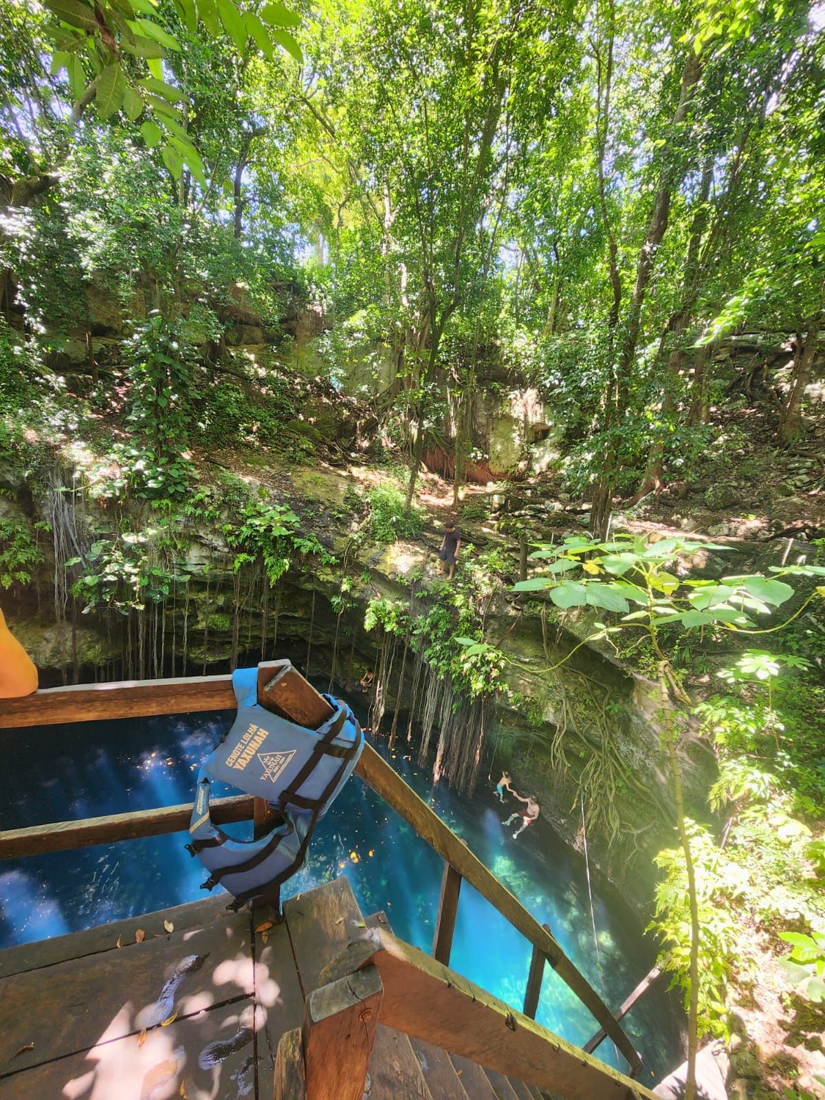 Looking down into a cenote — turquoise water beneath a wooden platform